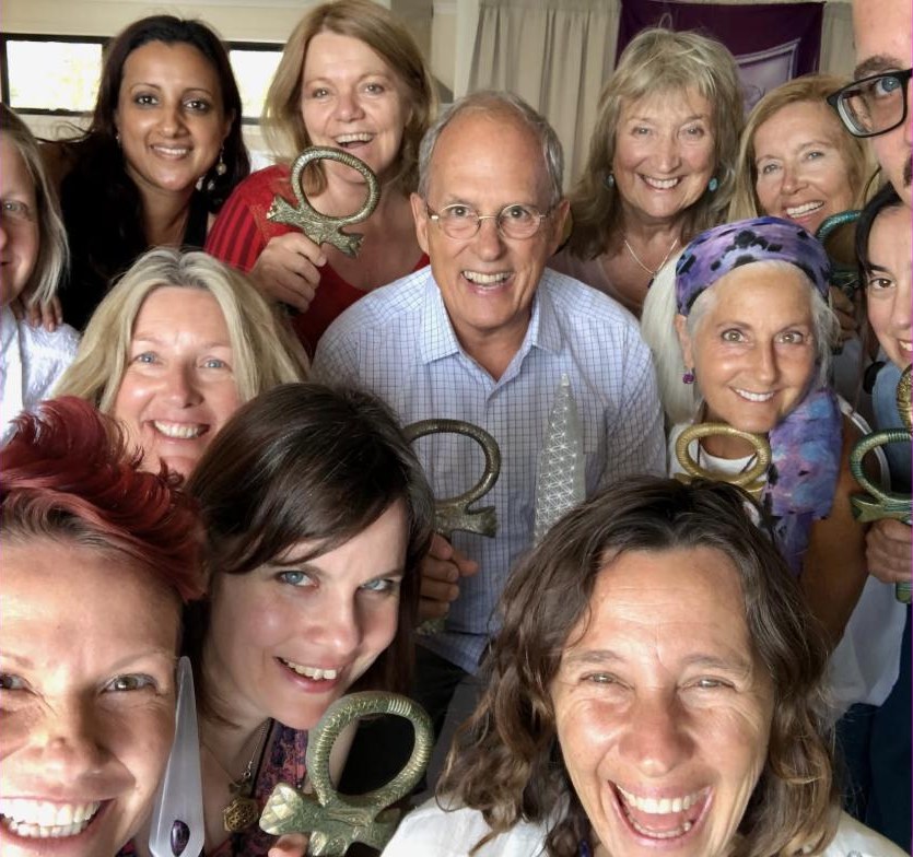 A group of workshop participants gathered close together holding bronze ankhs and a Selenite Sword of Light, Tom Ledder among them