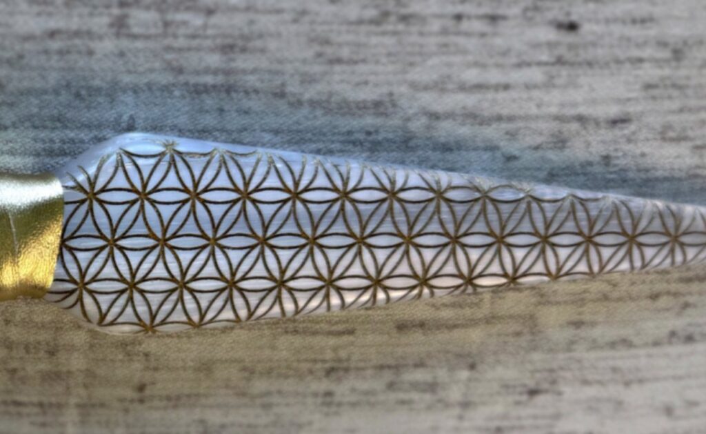 Close view of a selenite blade engraved edge to edge with the Flower of Life