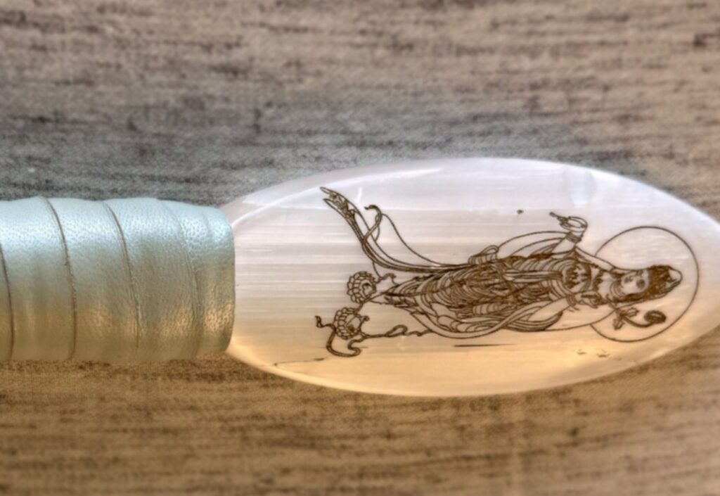 Close view of a selenite blade engraved with a figure of Quan Yin riding a dragon